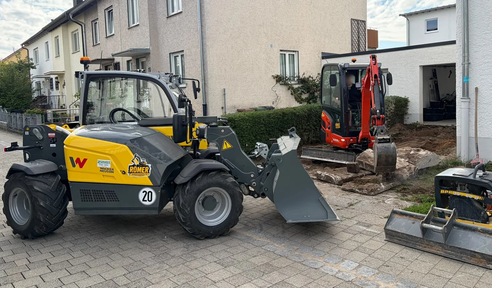 Radlader und Kubota Minibagger von Baumaschinenverleih-Römer bei Erdarbeiten an einem Wohnhaus